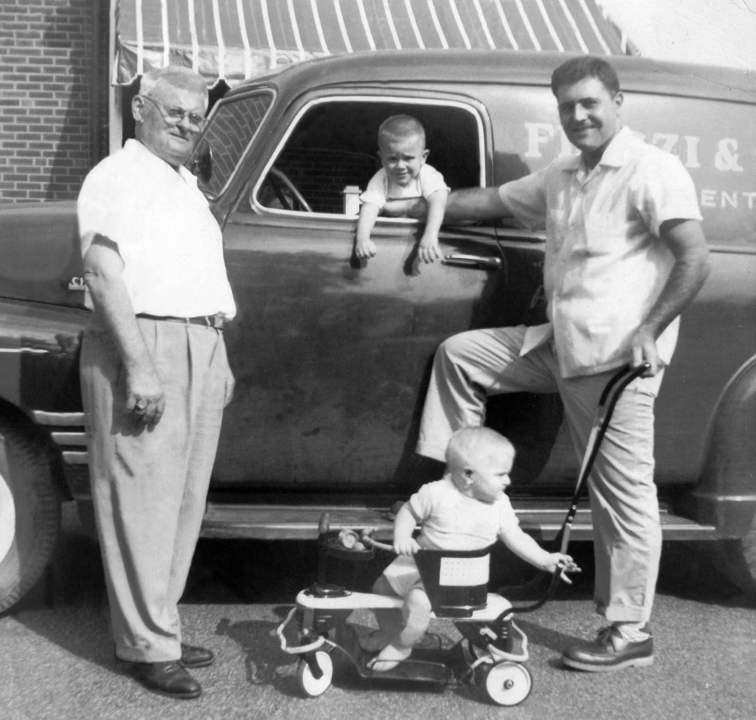 Photo courtesy Dan Frizzi, Jr. Pictured is the Frizzi & Son delivery truck with the author’s grandfather Abe (left) , his dad, him in the truck and his brother, Dick in the stroller, about 1954.