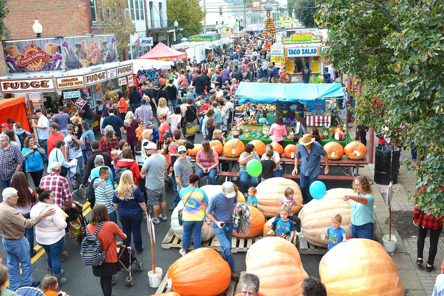 Crowds enjoying The Barnesville Pumpkin Festival with some of the giant pumpkins in the foreground.
