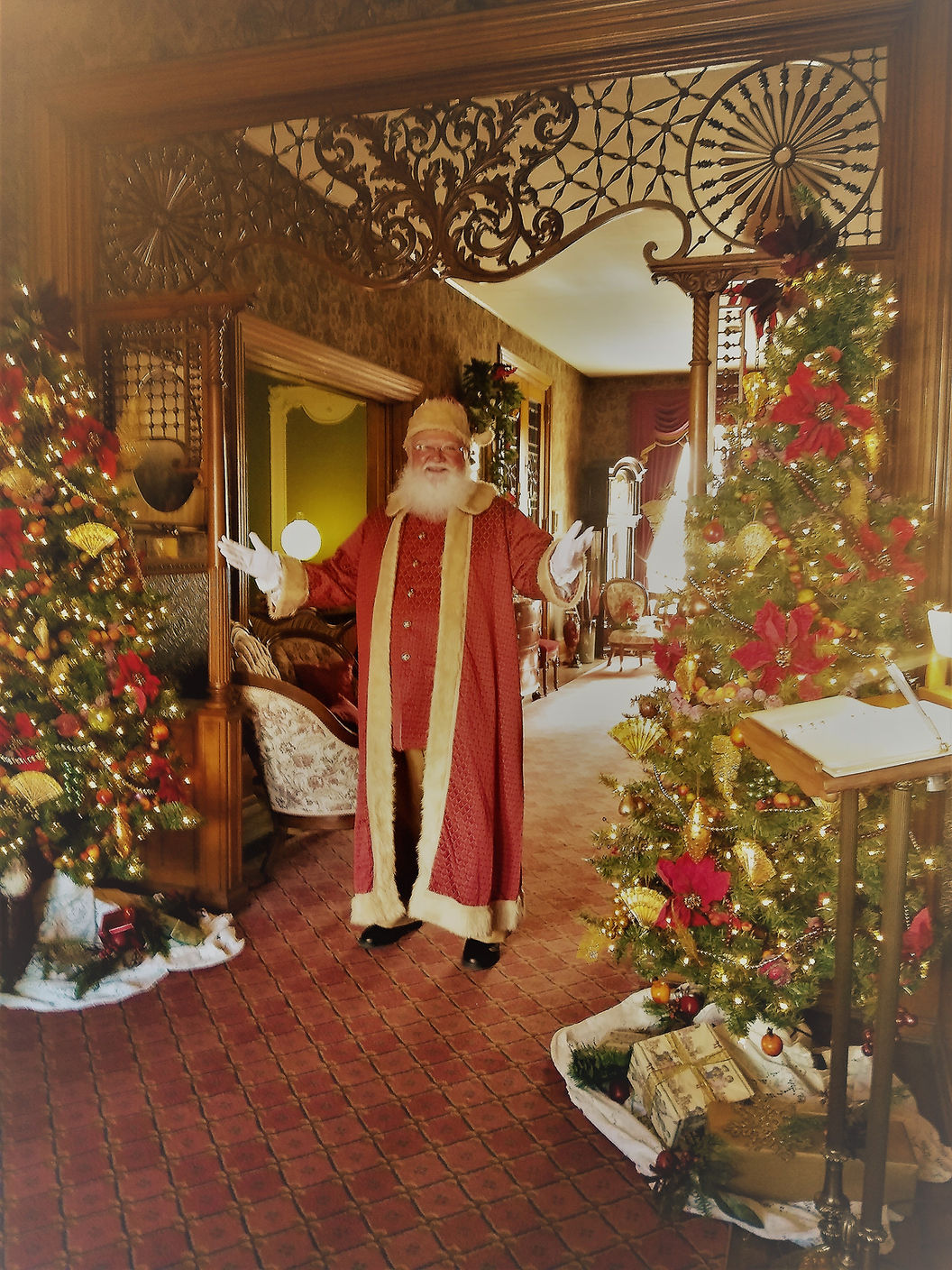 Santa standing in front of Christmas trees in the hallway